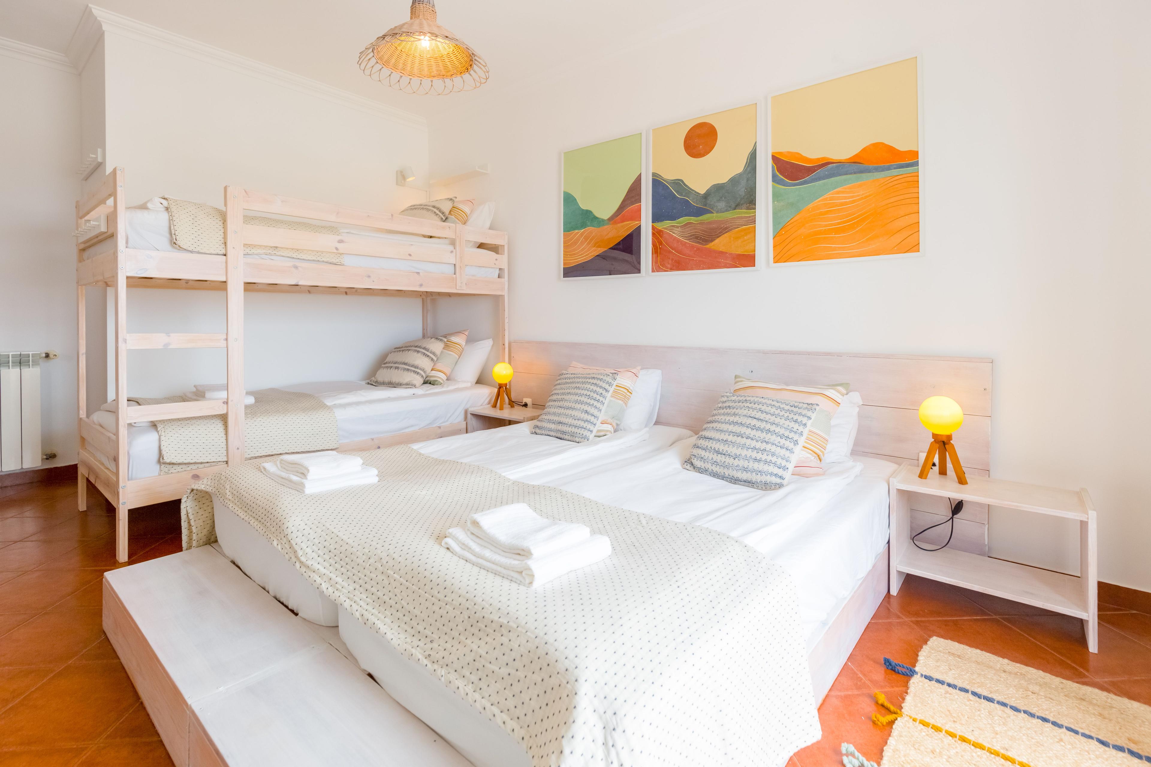 Ljust och mysigt sovrum med fyra sängar, pastellfärger.