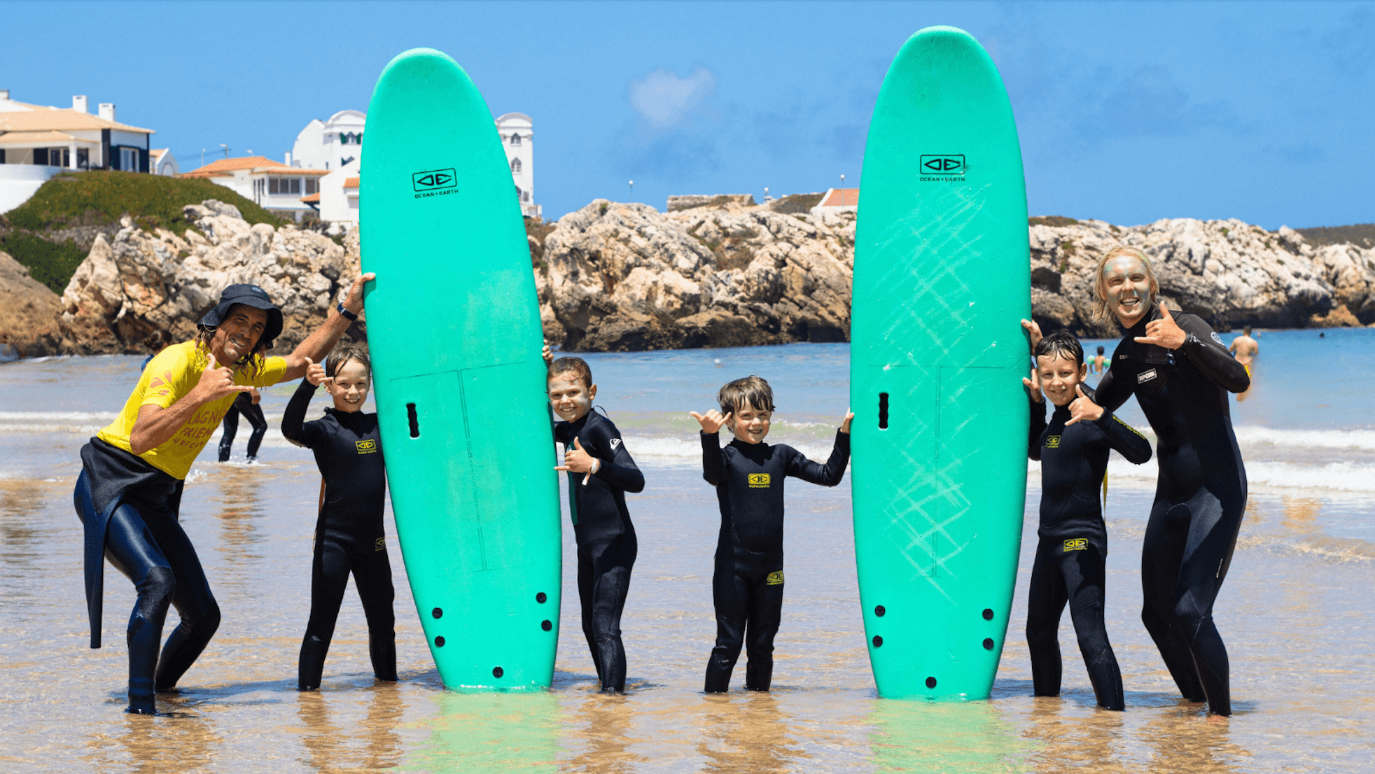 Surfinstruktörer och barn som står i vattnet och poserar med surfbrädor