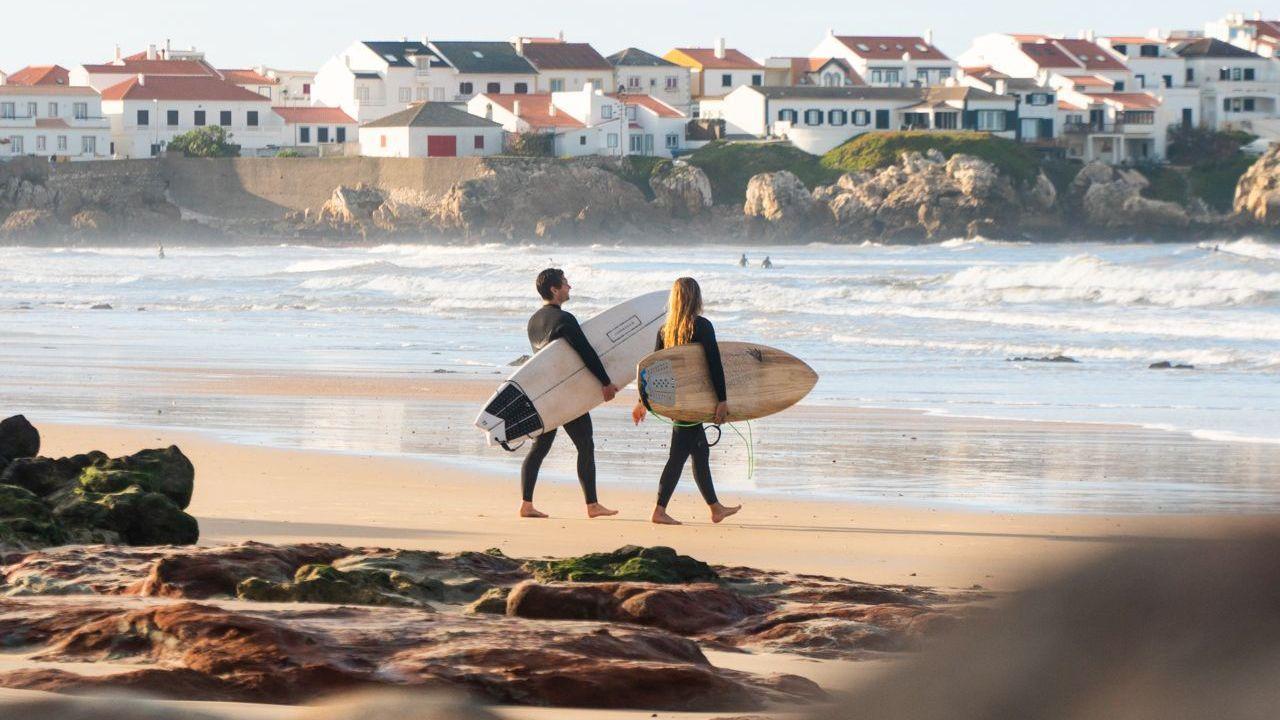 Två surfare som är påväg ut i vattnet för att fånga några vågor i Baleal, Portugal