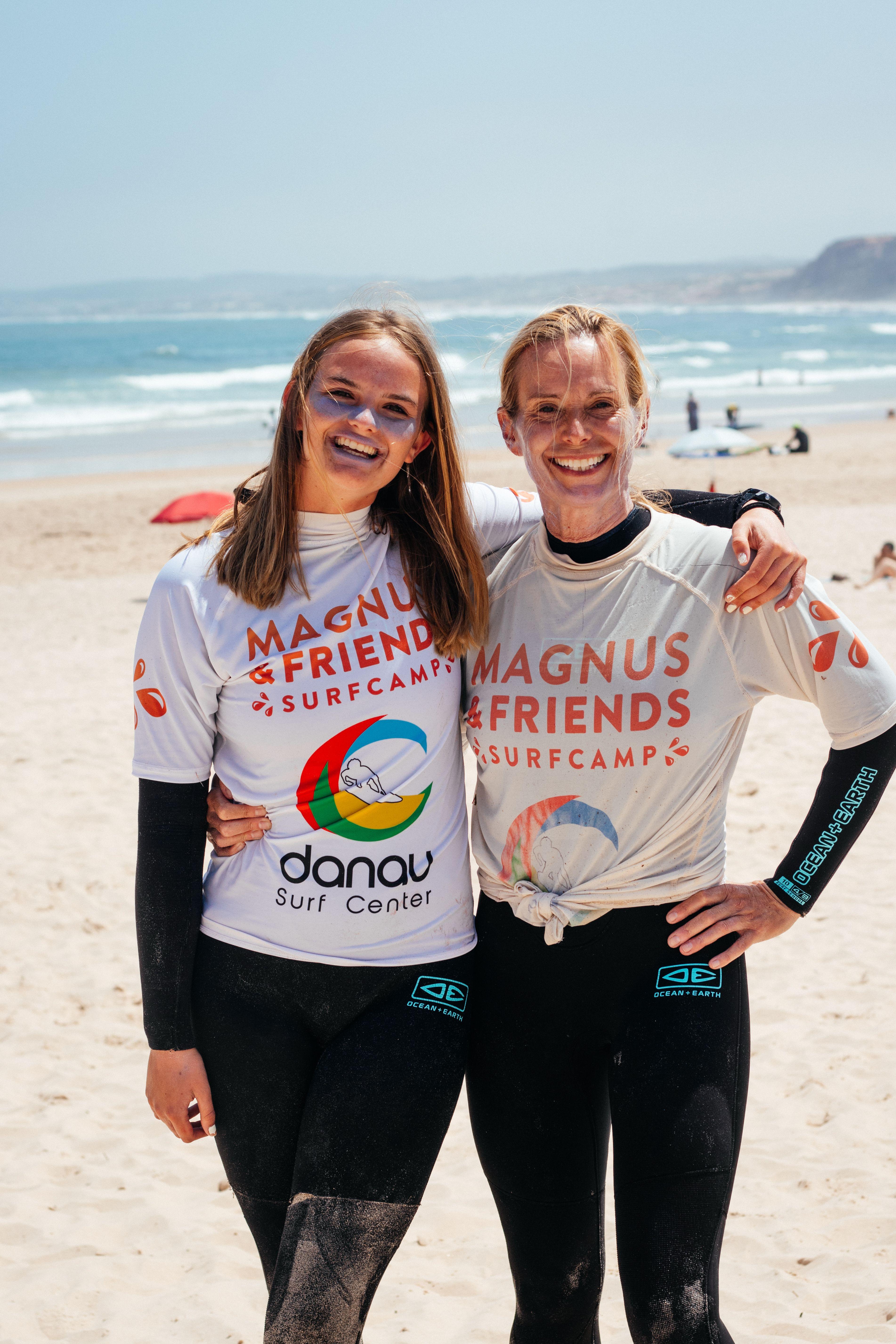 Mamma och dotter på stranden glada innan surflektion