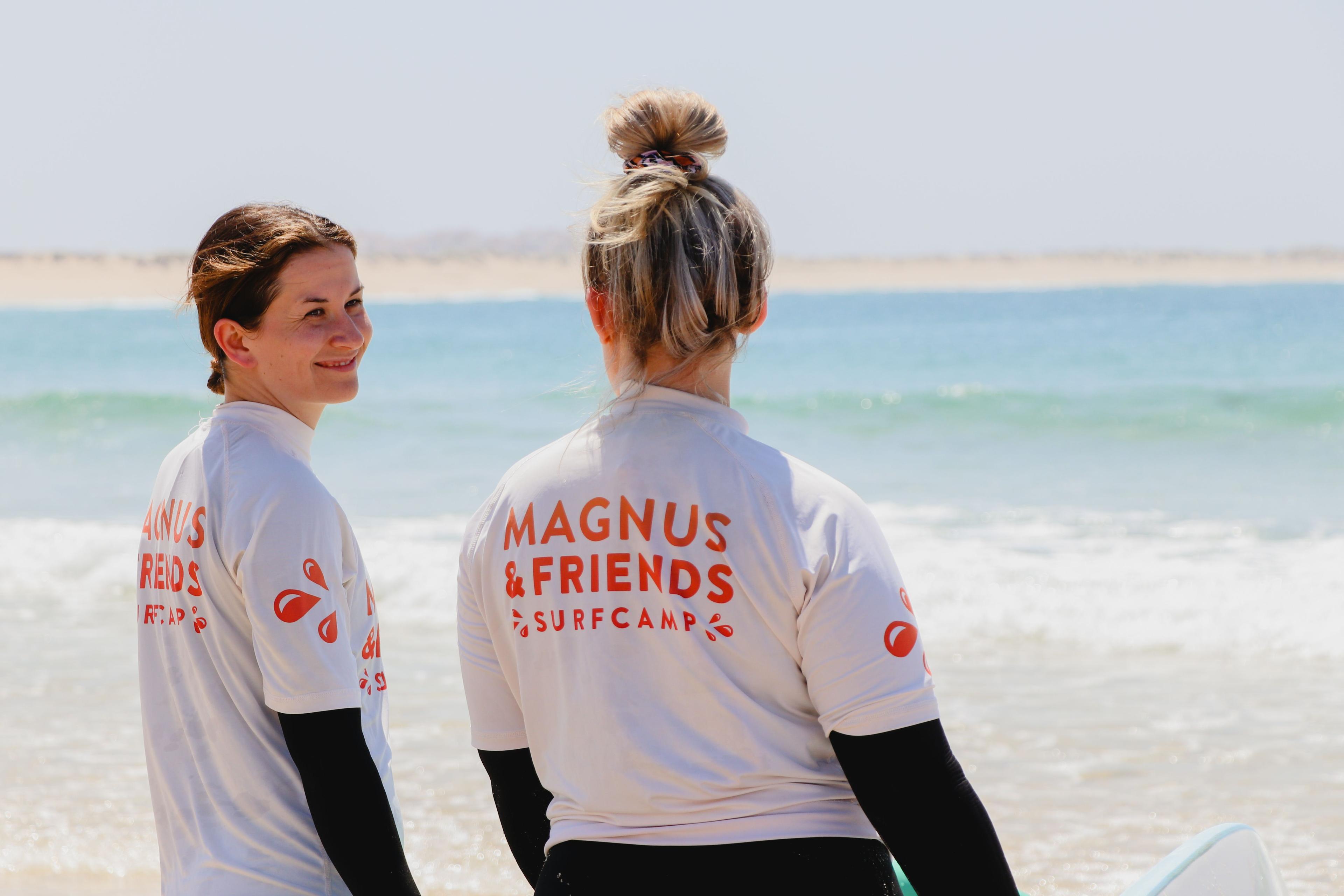 Två tjejer från Friendcation som står vid strandens kant med Magnus & friends tröjor.