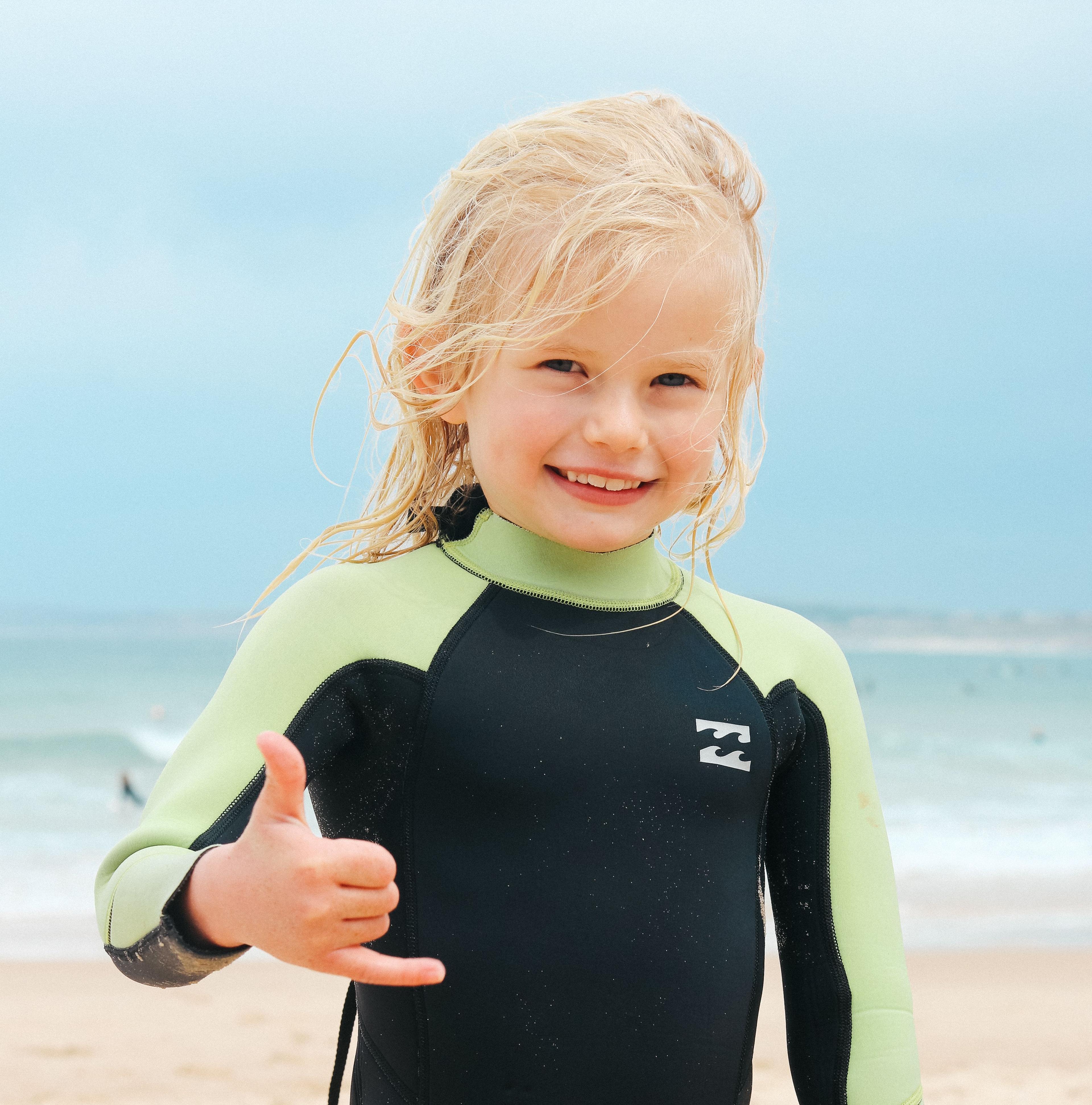 Liten tjej på stranden glad efter sin surflektion