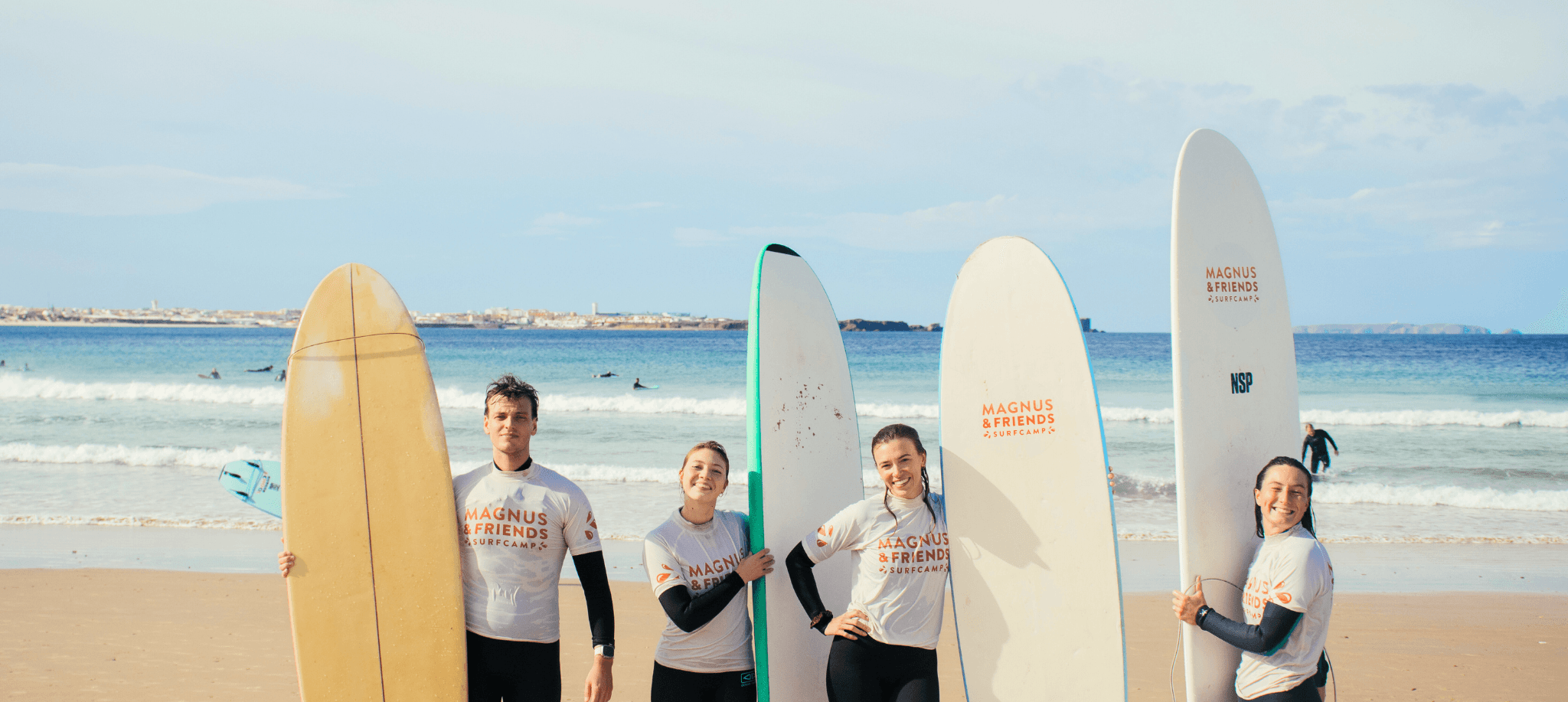 Glada surfare som poserar med sina surfbrädor på stranden