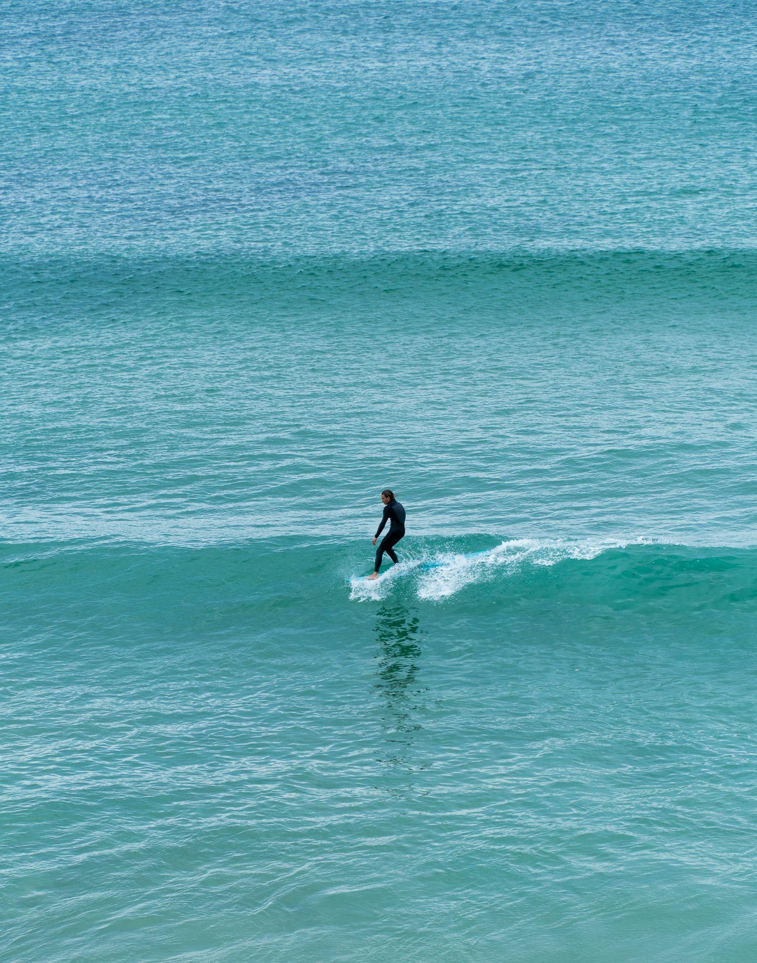 Surfare på en longboard på en grön våg vid Baleals kust i Portugal