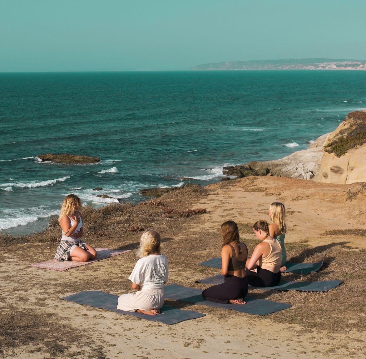 Yoga på klipporna med havet i bakgrunden