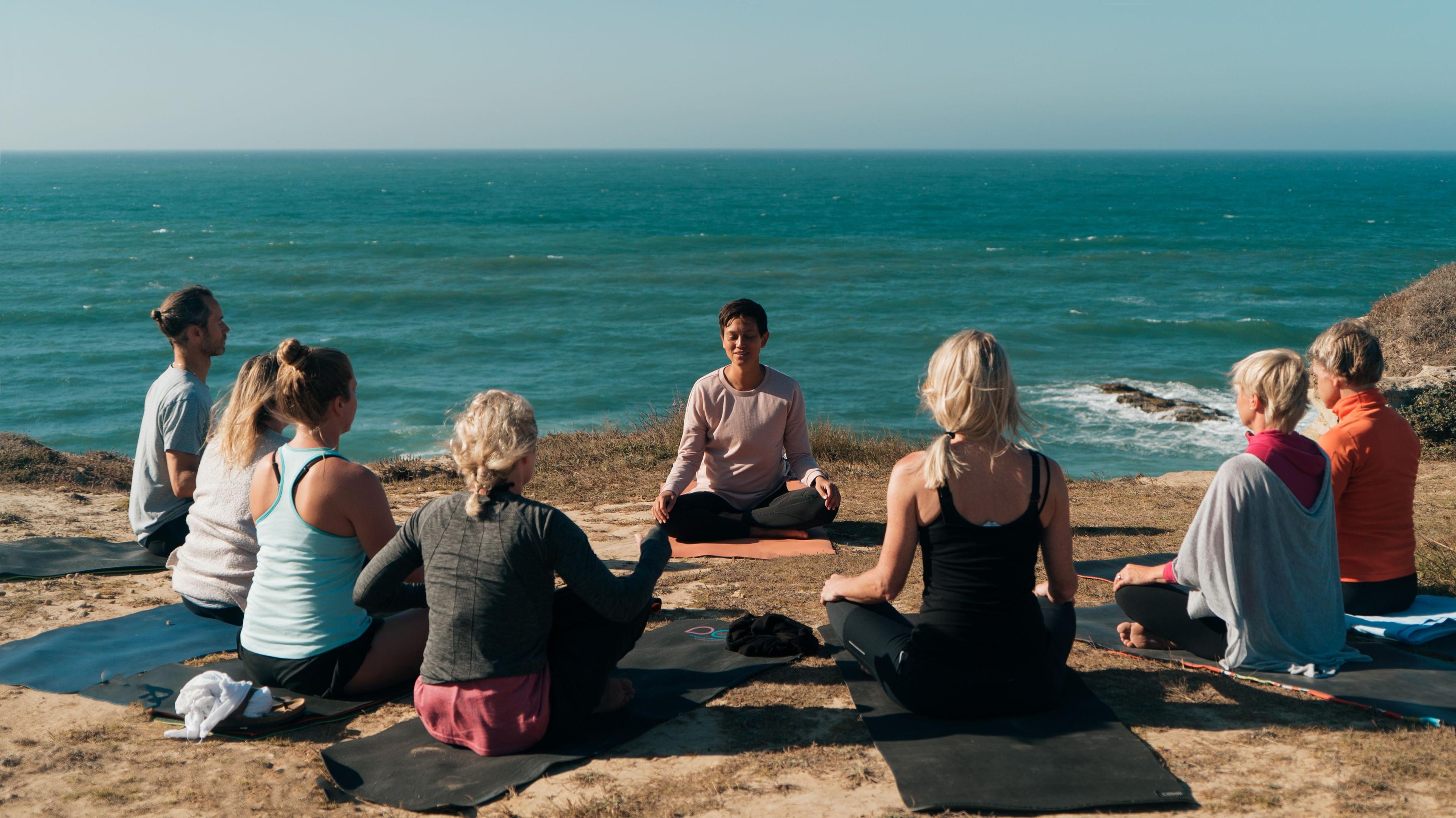 En yogagrupp på klipporna med havet i bakgrunden