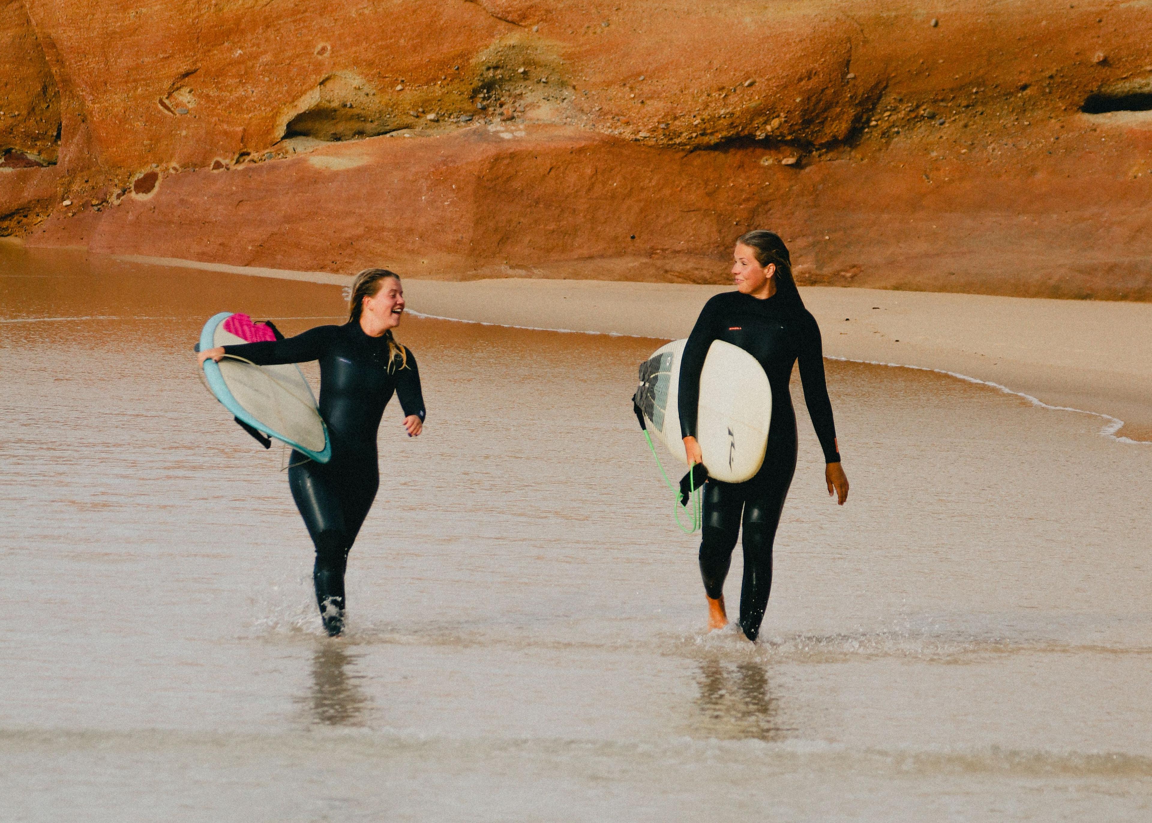 Två surfare som går längs en strand med sina surfbrädor