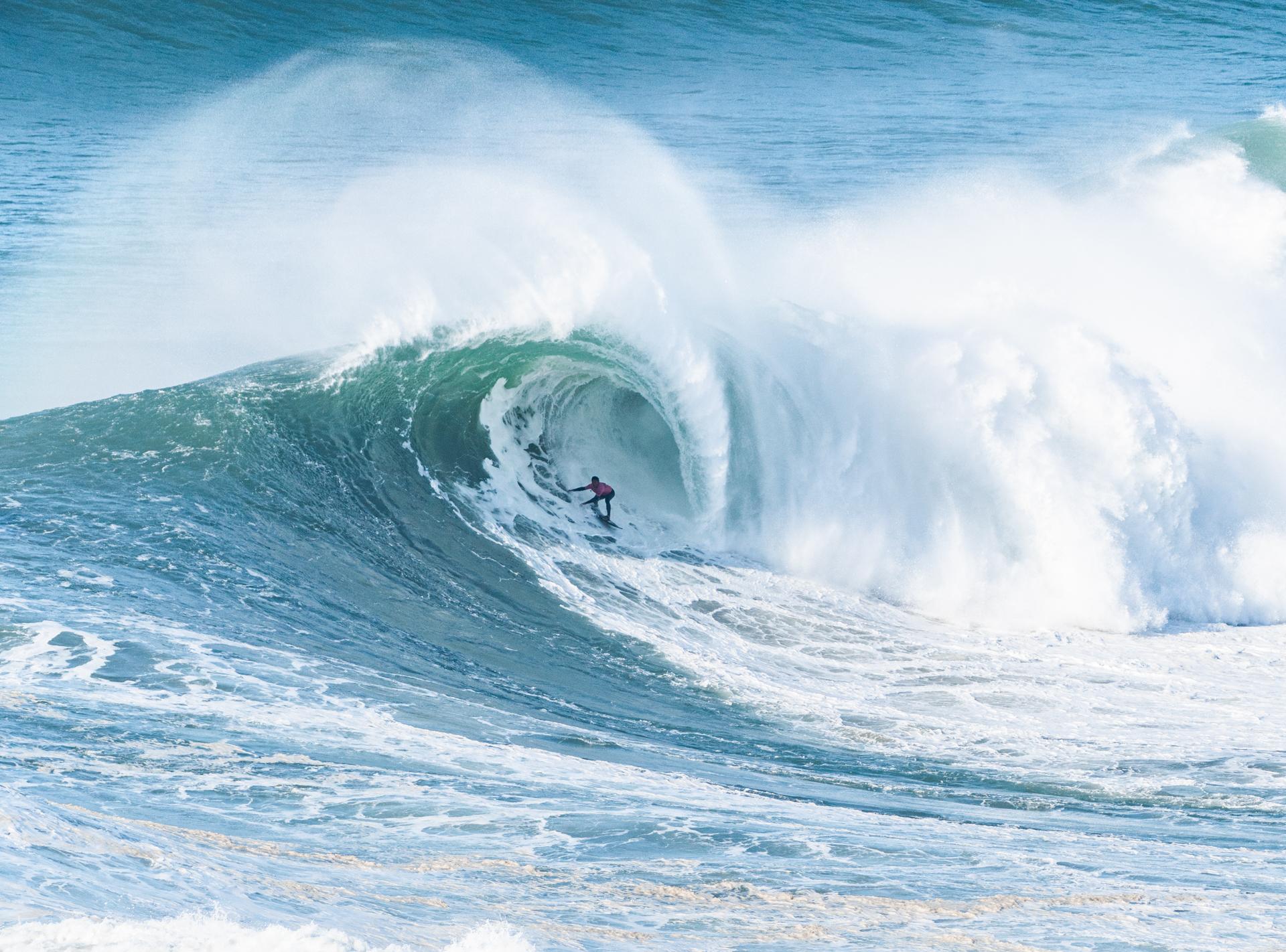  En surfare glider genom en massiv våg i Nazaré