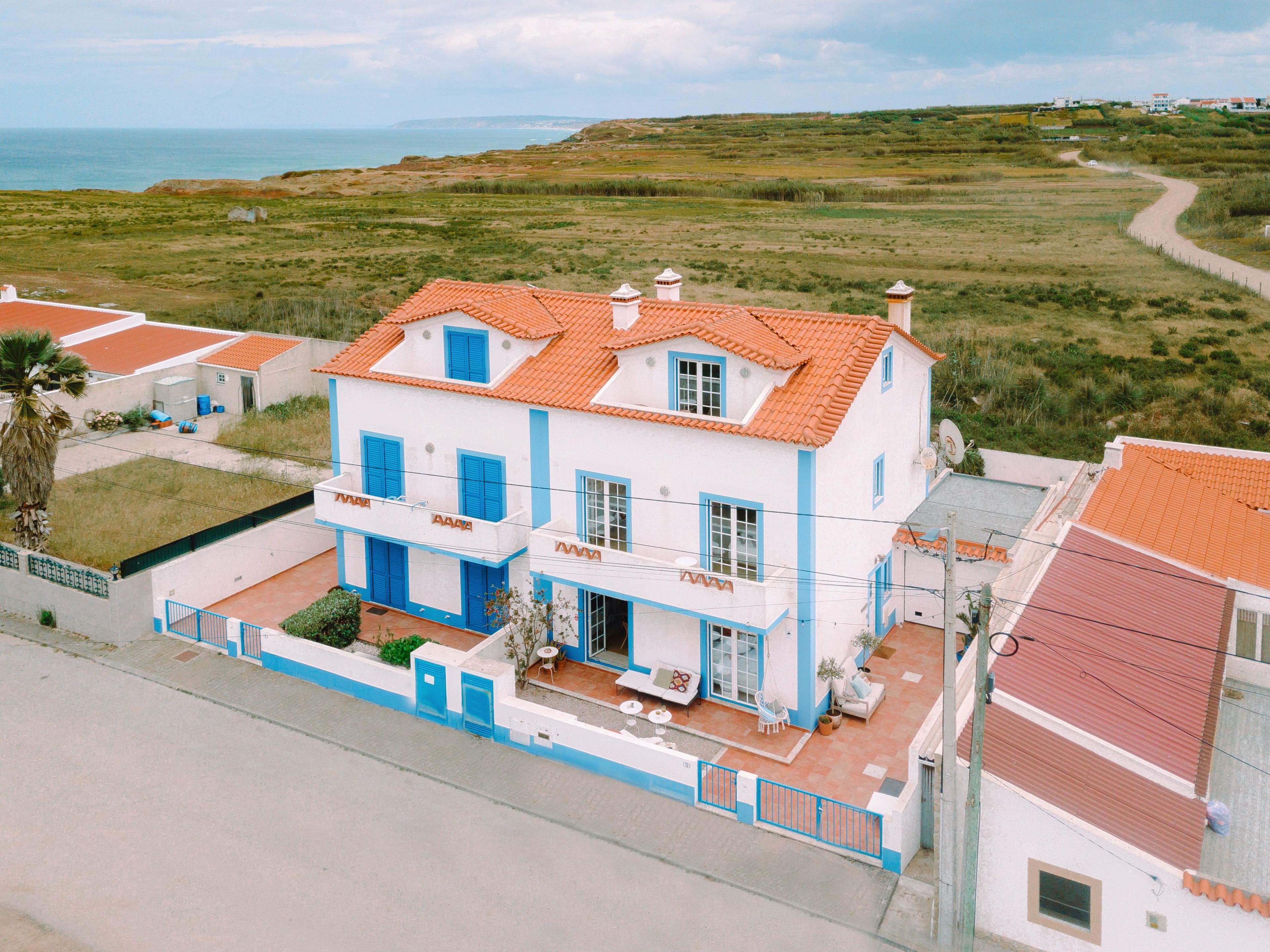 Flygbild av ett mysigt surfhus med vita väggar och blå fönsterluckor, nära havet i Baleal, Portugal