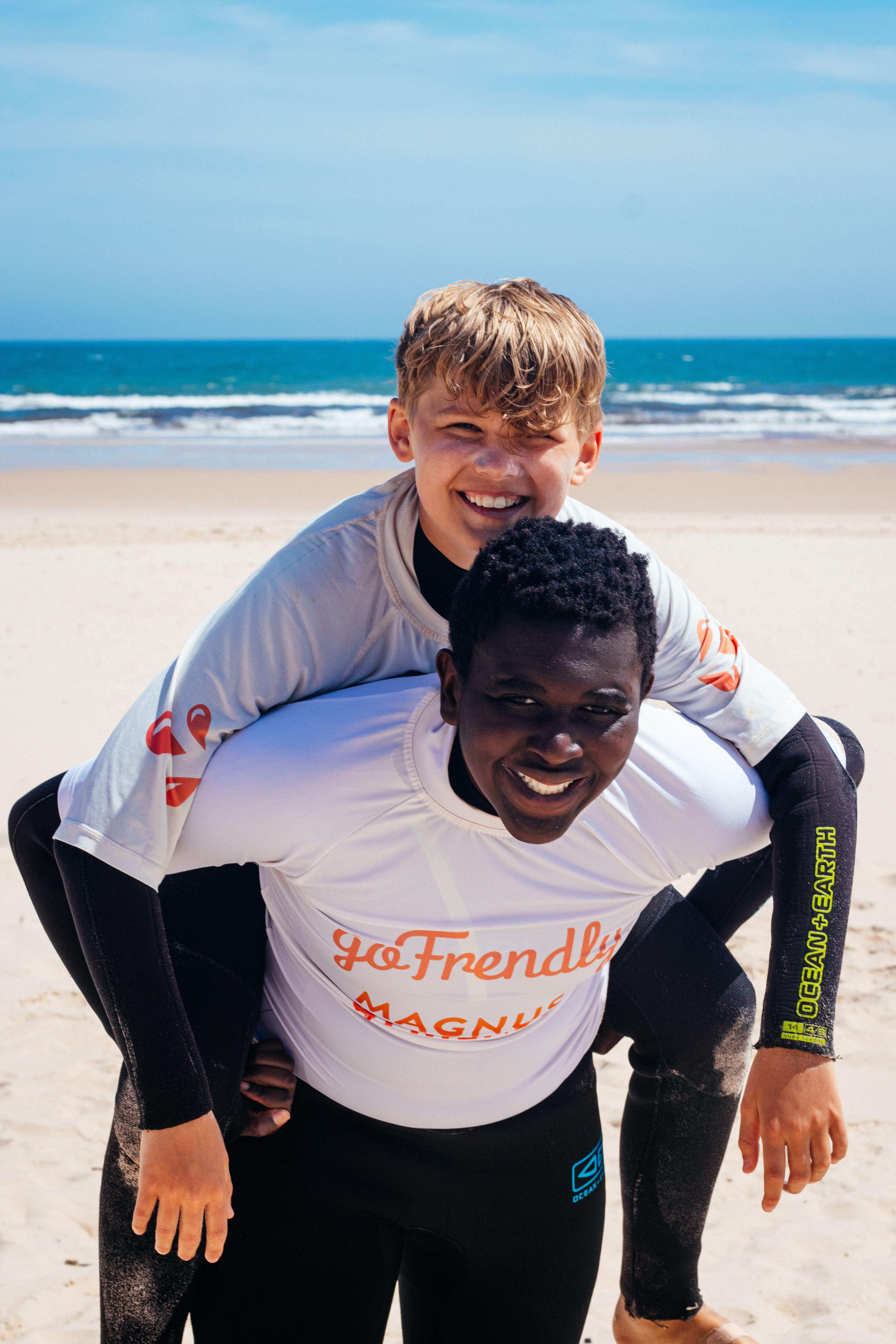 Två glada ungdomar i våtdräkter på stranden efter en surflektion vid Magnus & friends surfcamp i Portugal