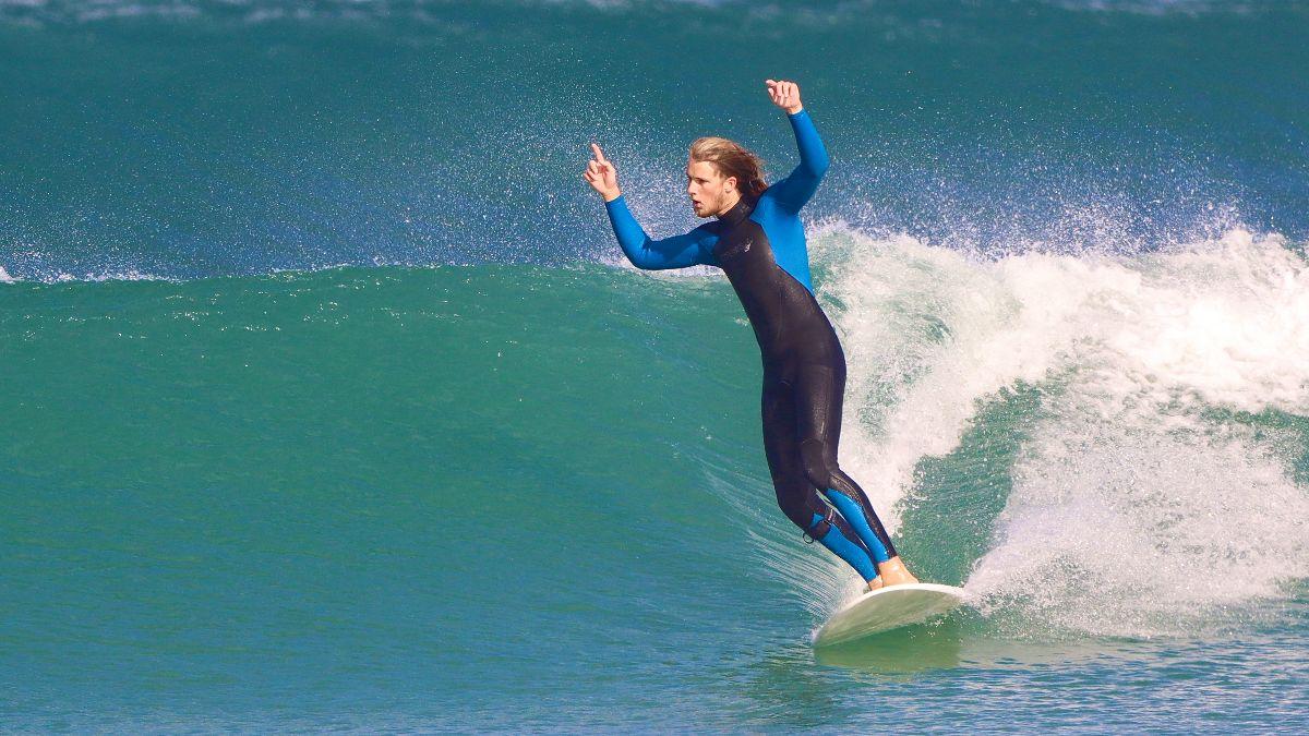 Surfare glider avslappnat på en våg under surfguiding i Baleal, Portugal