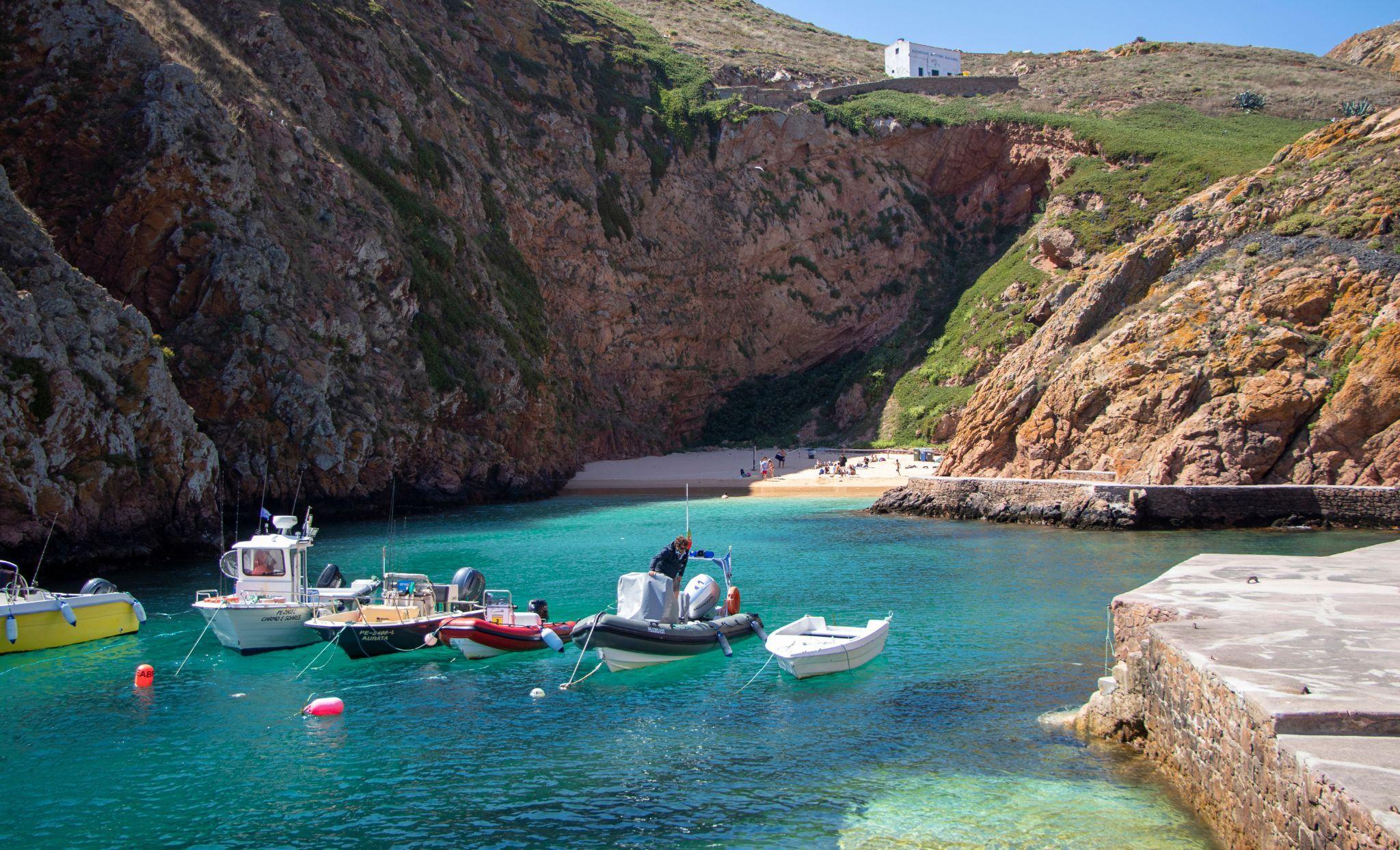 Båtar i turkost vatten vid Berlengas med strand och klippor i bakgrunden