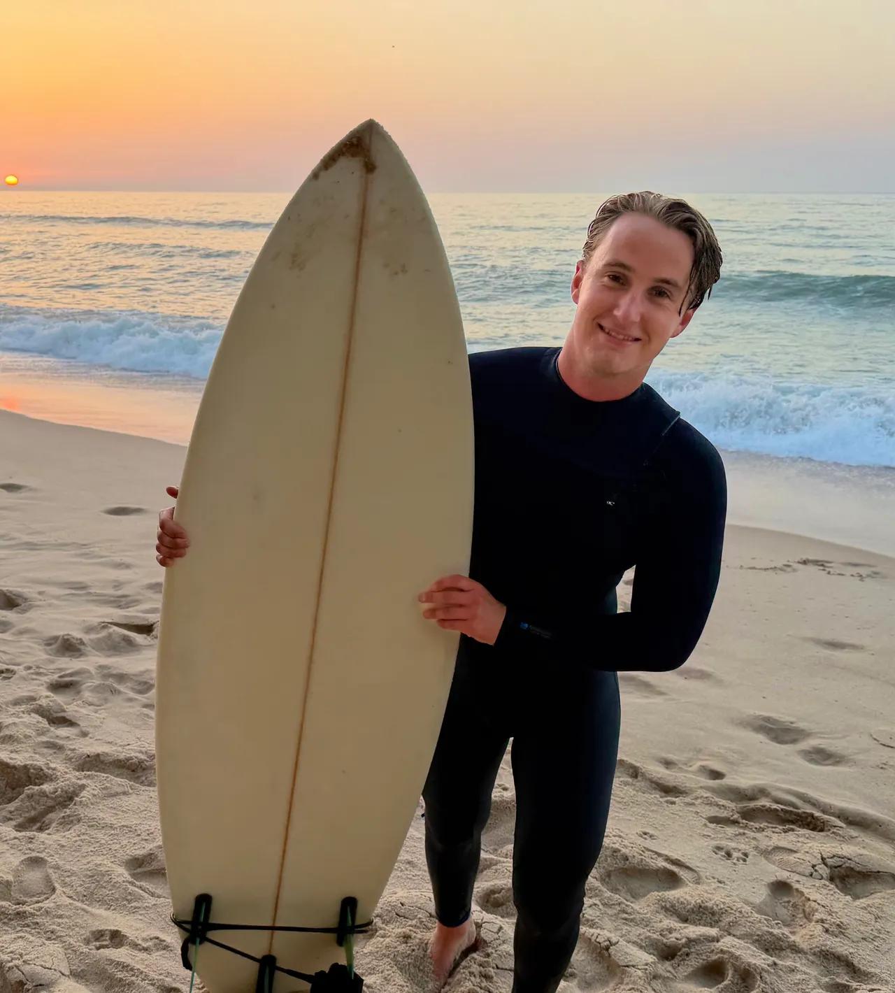 Kille med surfbräda på stranden i Portugal