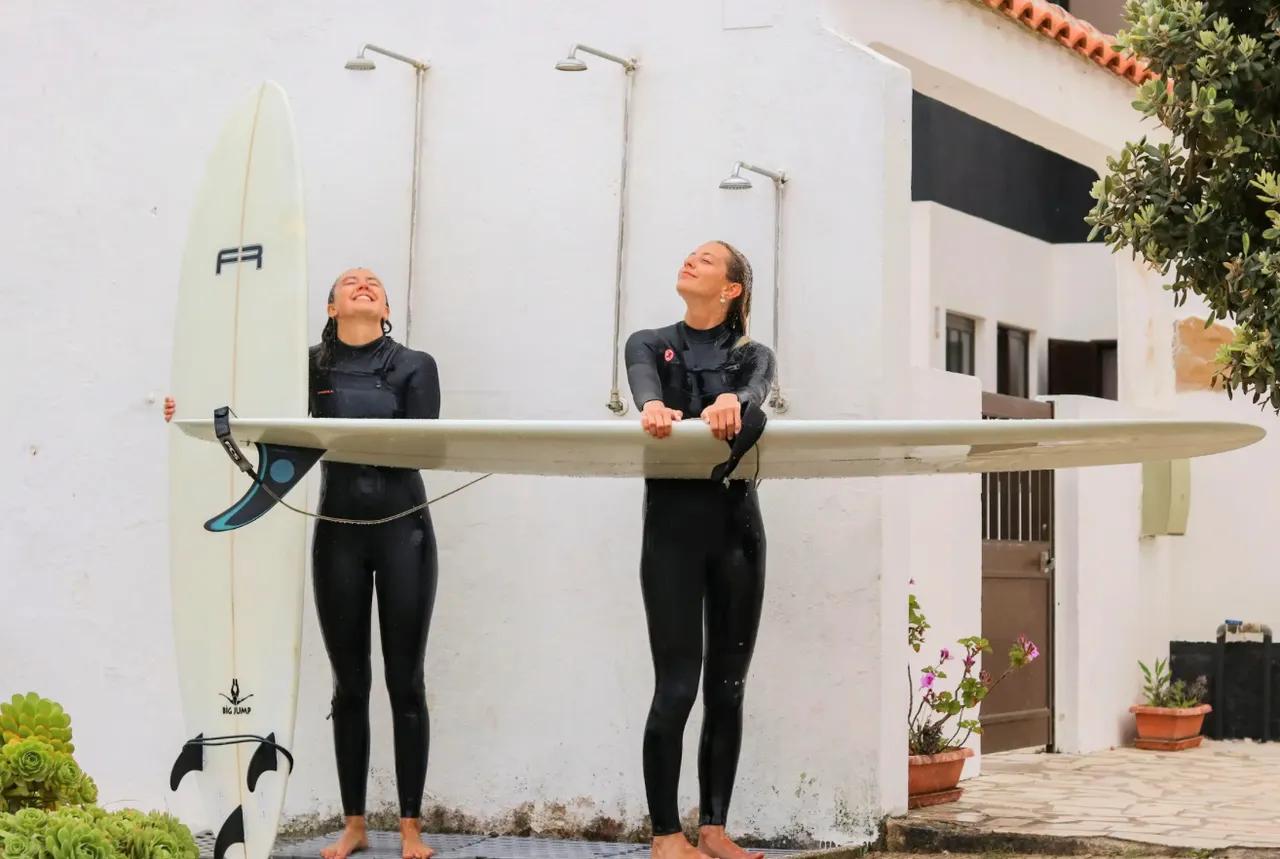 Två tjejer som håller i surfbräda