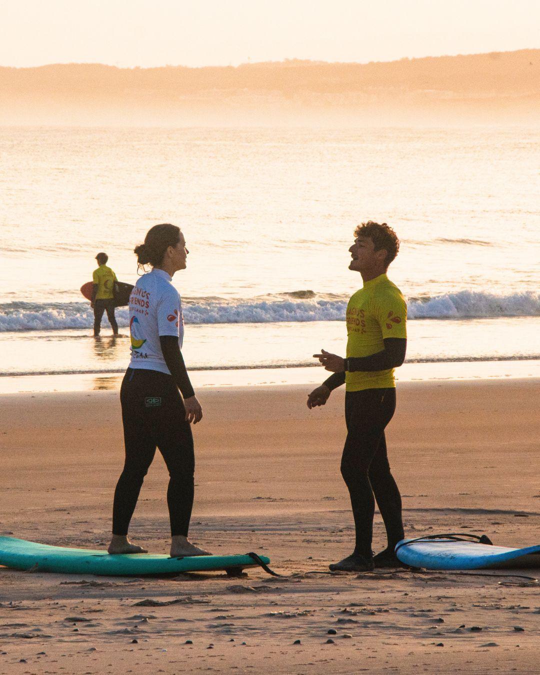 Instruktör Rodrigo och gäst som värmer upp inför sunrise surf på stranden i Baleal, Peniche.